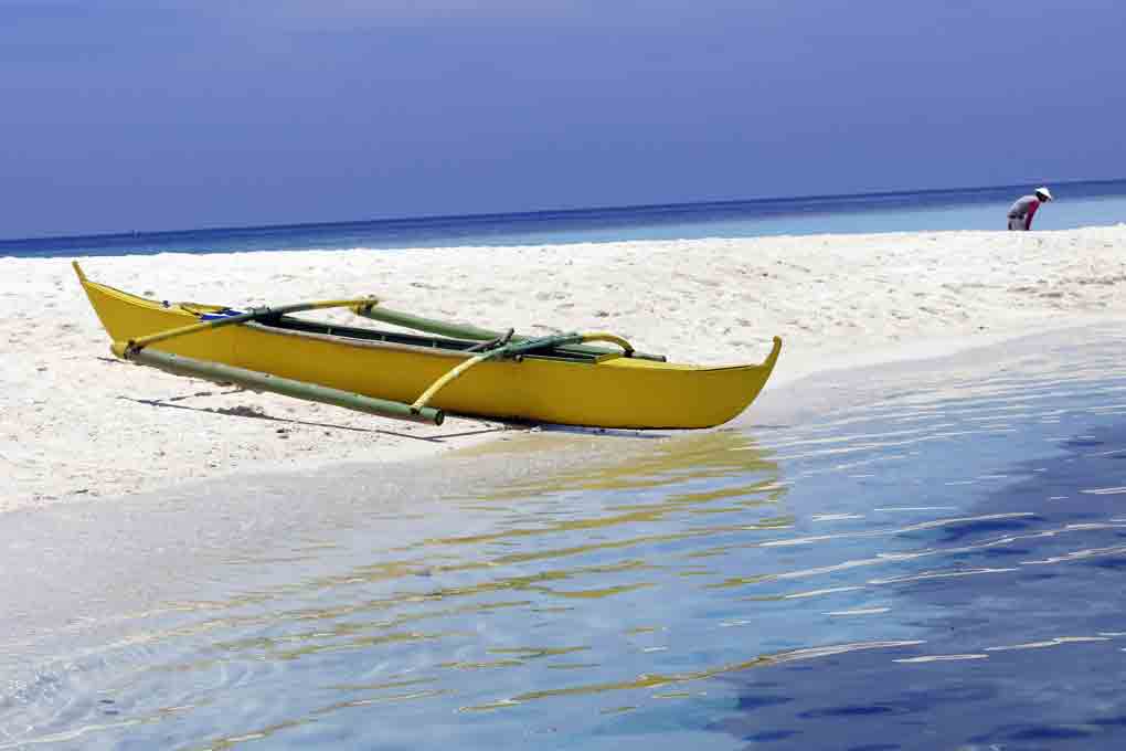 Une bangka sur du sable blanc aux Philippines